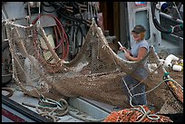 Woman repairing net on fishing boat. Whittier, Alaska, USA