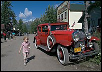 Girl on main street with red classic car. McCarthy, Alaska, USA