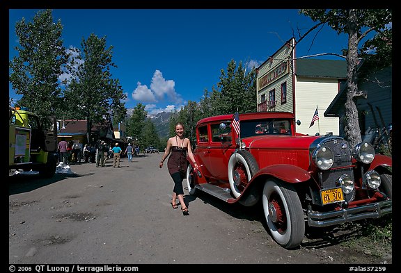 Woman walking next to red classic car. McCarthy, Alaska, USA