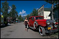 Woman walking next to red classic car. McCarthy, Alaska, USA ( color)