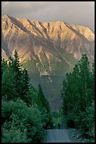 People strolling on unpaved path, with sunset light on mountains. McCarthy, Alaska, USA ( color)