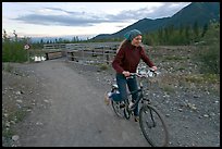 Woman on mountain bike with bridge behind. McCarthy, Alaska, USA