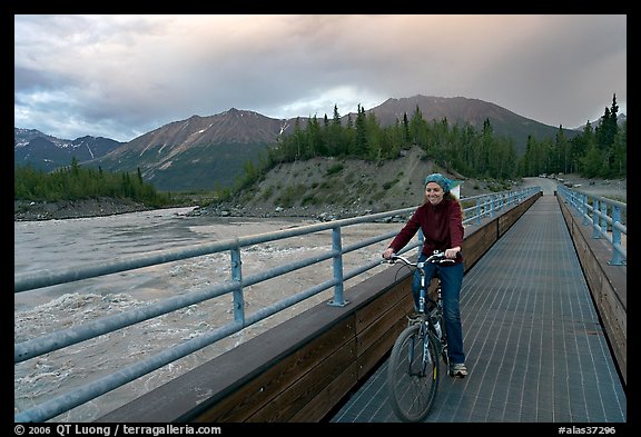 Woman on mountain bike crossing the footbridge. McCarthy, Alaska, USA (color)