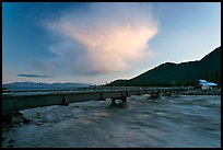 Kennicott River swelled from the Hidden Lake flood rushing against footbridge, sunset. McCarthy, Alaska, USA