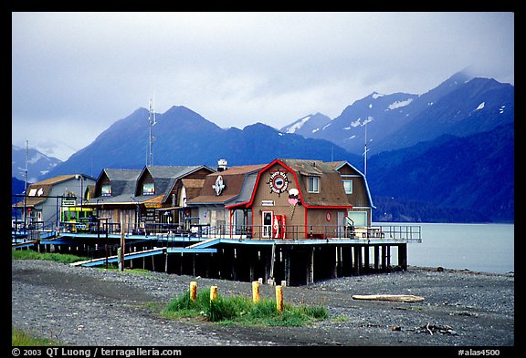 Stilt houses on the Spit, Kenai Mountains in the backgound. Homer, Alaska, USA (color)
