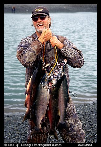 Man carrying salmon freshly caught in the Fishing Hole. Homer, Alaska, USA (color)