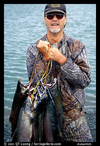 Fisherman carrying salmon freshly caught in the Fishing Hole. Homer, Alaska, USA (color)