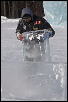 Ice carver lifting ice block. Fairbanks, Alaska, USA