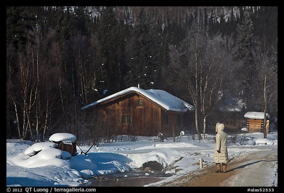 Woman with winter coat walking on path to cabins. Chena Hot Springs, Alaska, USA