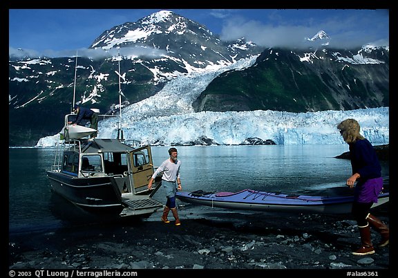 Kayakers unload  kayak from  water taxi boat at Black Sand Beach. Prince William Sound, Alaska, USA