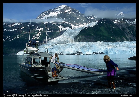 Man and woman  unload  kayak from the water taxi boat at Black Sand Beach. Prince William Sound, Alaska, USA (color)