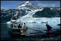 Man and woman  unload  kayak from the water taxi boat at Black Sand Beach. Prince William Sound, Alaska, USA