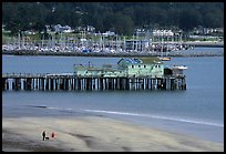 Couple on the beach and pier, Pillar Point Harbor. Half Moon Bay, California, USA (color)