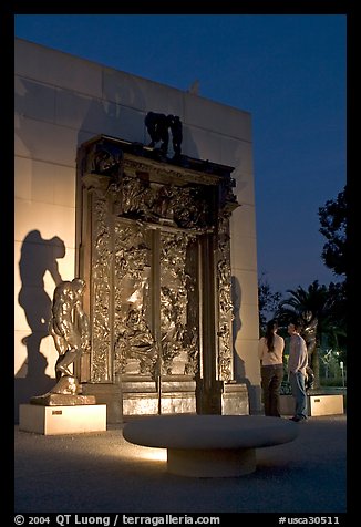 A couple contemplates Rodin's Gates of Hell at night. Stanford University, California, USA (color)