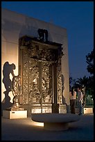 A couple contemplates Rodin's Gates of Hell at night. Stanford University, California, USA (color)