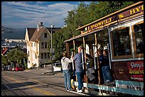 Cable car plunging with people clinging on Hyde Street, late afternoon. San Francisco, California, USA (color)