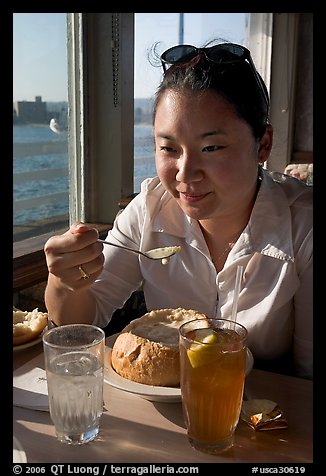 Woman eating a bown of clam chowder on the pier. Santa Cruz, California, USA (color)