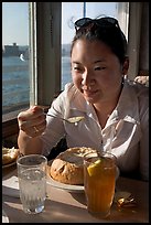 Woman eating a bown of clam chowder on the pier. Santa Cruz, California, USA