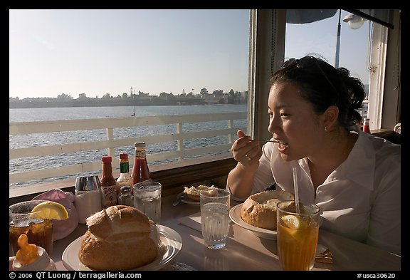Woman eating clam chowder in a sourdough bread bowl. Santa Cruz, California, USA