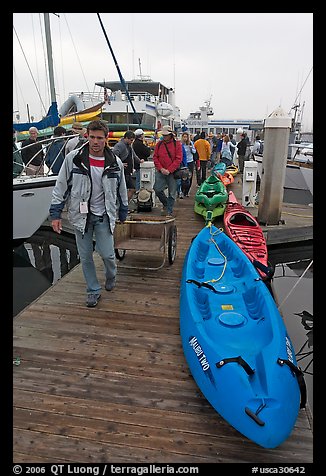 Sea kayaks and passengers awaiting loading on tour boat. California, USA