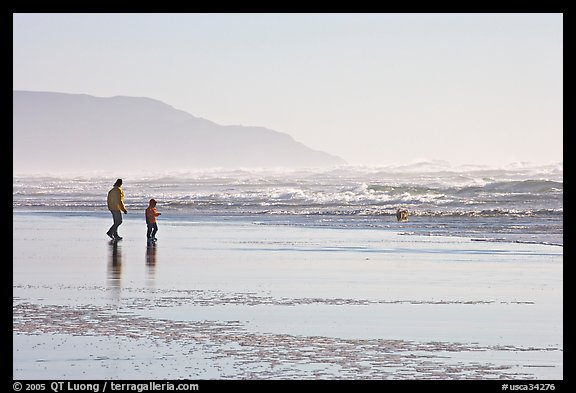 Man and child on wet beach, afternoon. San Francisco, California, USA (color)
