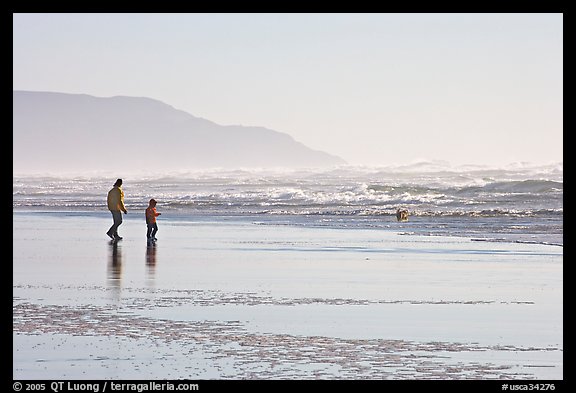 Man and child on wet beach, afternoon. San Francisco, California, USA