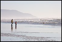 Man and child on wet beach, afternoon. San Francisco, California, USA (color)
