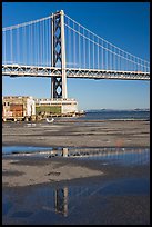 Bay Bridge reflected in water puddles. San Francisco, California, USA