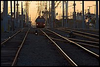 Railroad tracks, train, and power lines, sunrise. San Diego, California, USA