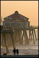 Beachgoers, surfers in waves,  and Huntington Pier. Huntington Beach, Orange County, California, USA (color)
