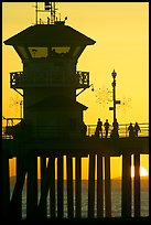 People and pier silhouetted by the setting sun. Huntington Beach, Orange County, California, USA