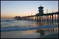 Huntington Pier reflected in wet sand at sunset. Huntington Beach, Orange County, California, USA