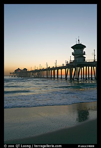 Huntington Pier and reflections in wet sand at sunset. Huntington Beach, Orange County, California, USA