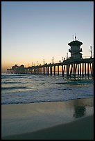 Huntington Pier and reflections in wet sand at sunset. Huntington Beach, Orange County, California, USA (color)