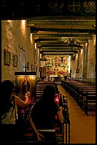 Two women light up candles in the Serra Chapel. San Juan Capistrano, Orange County, California, USA (color)