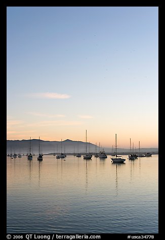 Yachts reflected in Morro Bay harbor, sunset. Morro Bay, USA (color)
