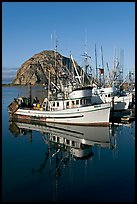 Fishing boats reflected in harbor,  and Morro Rock, early morning. Morro Bay, USA