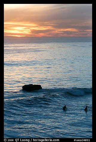 Surfers and rock at sunset. Santa Cruz, California, USA