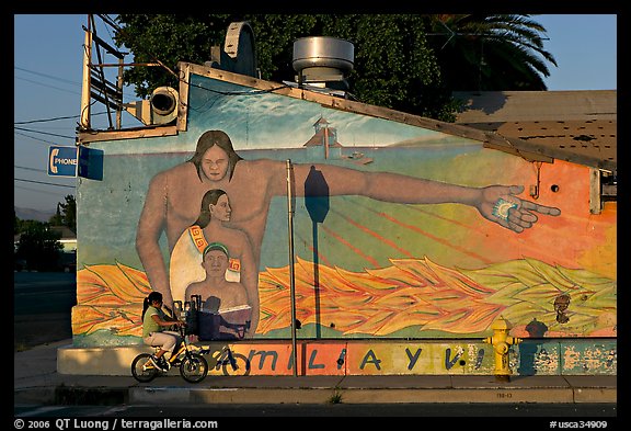 Hispanic girl on bicycle and mural, Alviso. San Jose, California, USA (color)