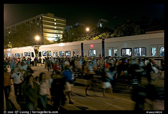 Crowds and light rail on San Carlos Avenue at night, Independence Day. San Jose, California, USA (color)