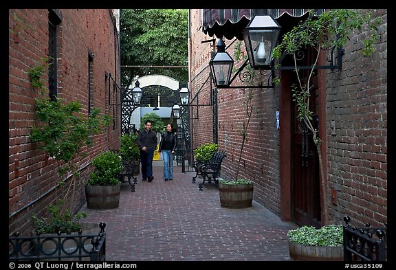 Couple walking in an alley of brick walls, San Pedro Square. San Jose, California, USA