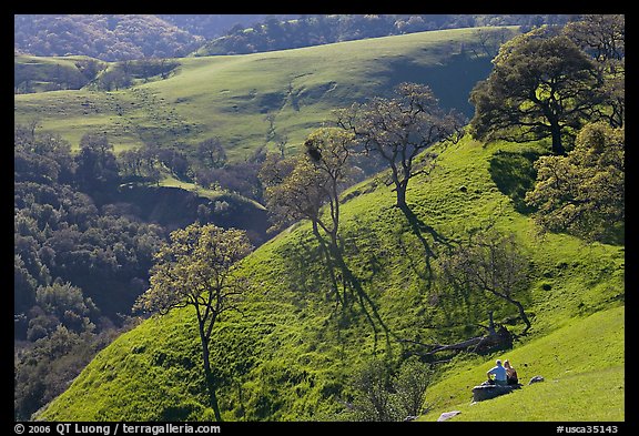 Couple sitting on hillside in early spring, Sunol Regional Park. California, USA