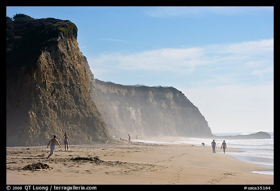 People strolling and playing below cliffs, Scott Creek Beach. California, USA