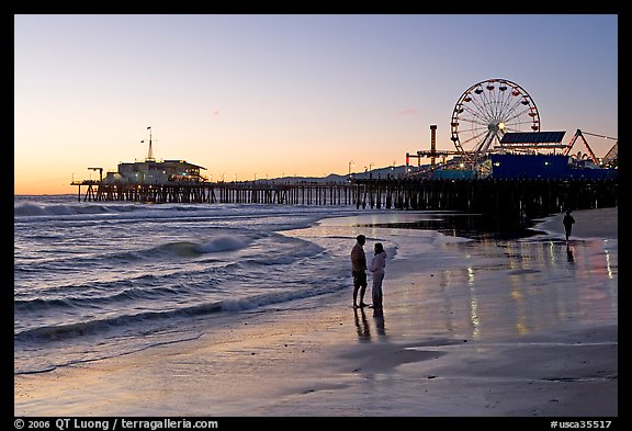 Couple on beach, with pier in the background, sunset. Santa Monica, Los Angeles, California, USA