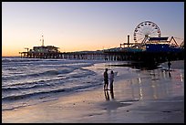 Couple on beach, with pier in the background, sunset. Santa Monica, Los Angeles, California, USA (color)