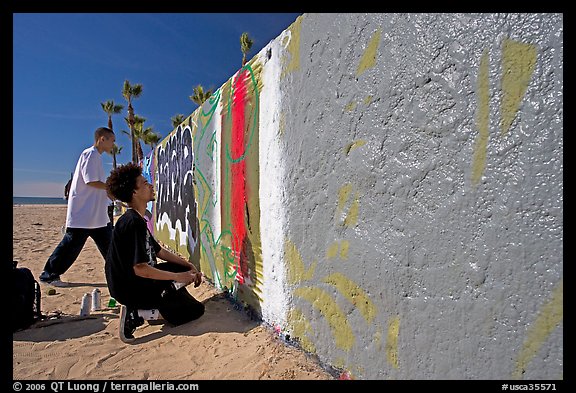 Young men creating graffiti art on a wall on the beach. Venice, Los Angeles, California, USA (color)