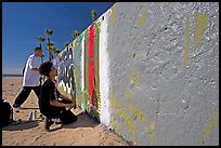 Young men creating graffiti art on a wall on the beach. Venice, Los Angeles, California, USA