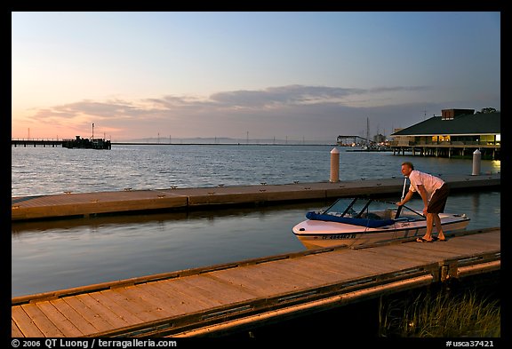 Man holding small boat, Redwood marina, sunset. Redwood City,  California, USA