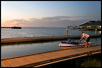 Man holding small boat, Redwood marina, sunset. Redwood City,  California, USA (color)