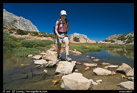 Woman crossing stream on rocks, John Muir Wilderness. California, USA (color)